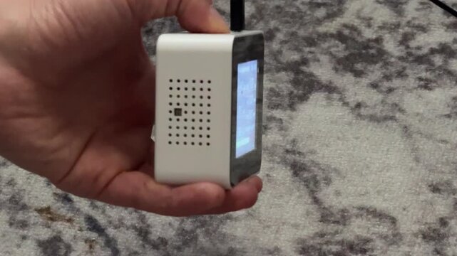 Person turning on air quality monitor device close up at home, activating sensor, measuring indoor air conditions, technology use concept
