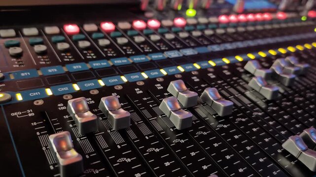 Automated faders moving on a digital audio mixing console during a soundcheck for a concert, a show, or a recording session in a professional music studio