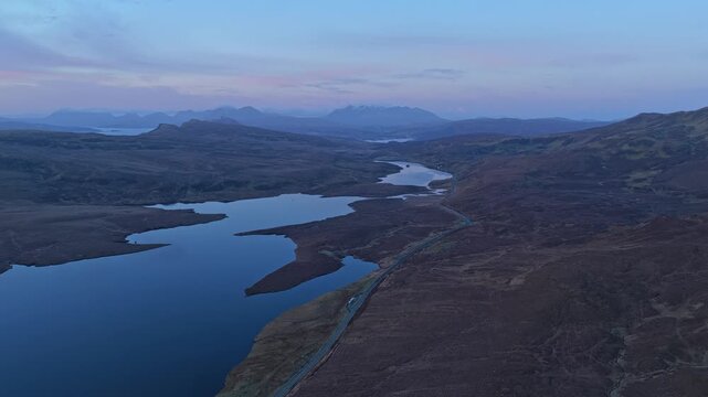 Majestic aerial perspective of the old man of storr and loch leathan in the scottish highlands. The twilight sky reflects on the calm water