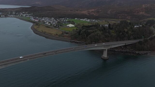 Majestic aerial view showing traffic flowing on the skye bridge connecting the isle of skye to the mainland under a dramatic, cloudy sky