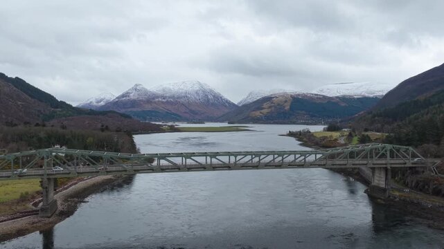 Majestic ballachulish bridge crossing loch leven with traffic moving. Stunning scottish highlands landscape with snow capped mountains in winter