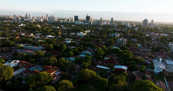 Aerial view of Asuncion at sunset showing residential neighborhoods, greenery, and modern skyline. Captures warm light and urban development in Paraguay&rsquo;s capital.