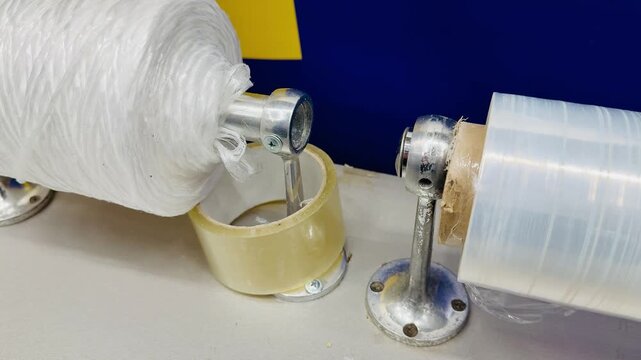 Transparent film white rope on counter showcasing closeup of dispenser with clear stretch film and dense white twine spool ready