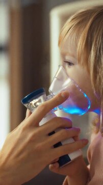 A mother's gentle hands position a nebulizer mask over her young daughter's face for inhalation therapy, soothing coughs and asthma, illustrating tender care in managing respiratory health