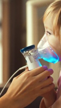 A nurturing parent guides their child through an aerosol therapy session, using a nebulizer to deliver cold medicine, loosen thick mucus and relieve congestion, while calmly explaining the process