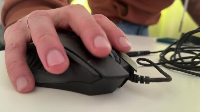 Hand using black computer mouse on desk close up, office work and productivity concept