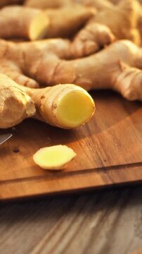 Fresh ginger rhizomes on a kitchen counter's cutting board release a pungent aroma, showcasing their vibrant, anti-inflammatory properties and rich vitamin and mineral content as they await chopping