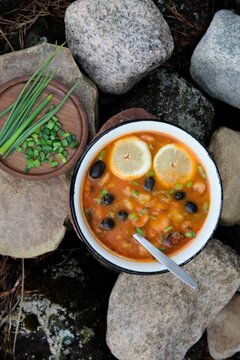 Funny surprised face concept with solyanka soup, overhead flat lay, lemon slices as shocked wide open eyes and spoon deeply inside the bowl, "caught with the spoon in mouth" creative food humor