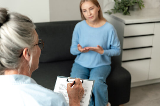 A therapist listens attentively to a patient in a comfortable living room