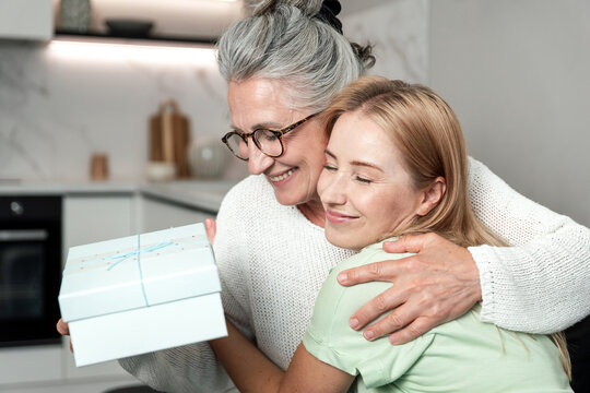 Elderly mother and adult daughter hugging, sharing a happy moment