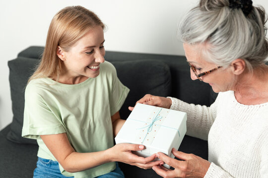 Happy adult daughter giving present to her mother