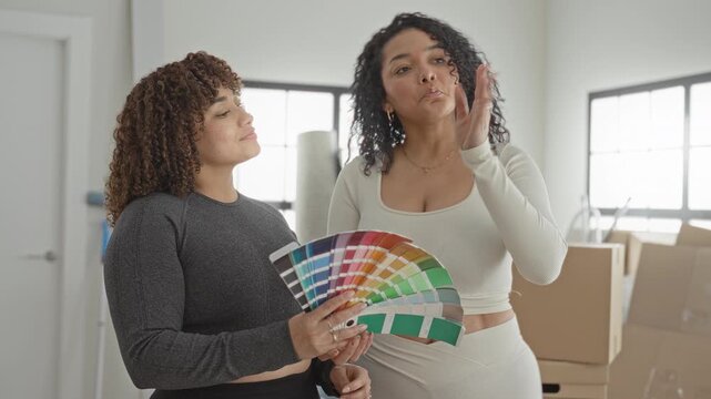 Woman holding paint swatches and pointing finger while choosing colors in a building room; design planning thoughtful.