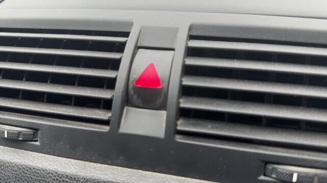 Car hazard warning signal blinking on dashboard button near air vent, vehicle safety alert and emergency driving concept