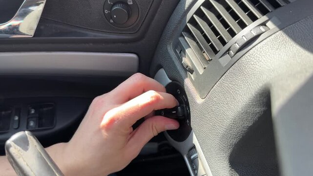 Hand switching car lighting modes on dashboard control, headlights and side lights automotive function concept