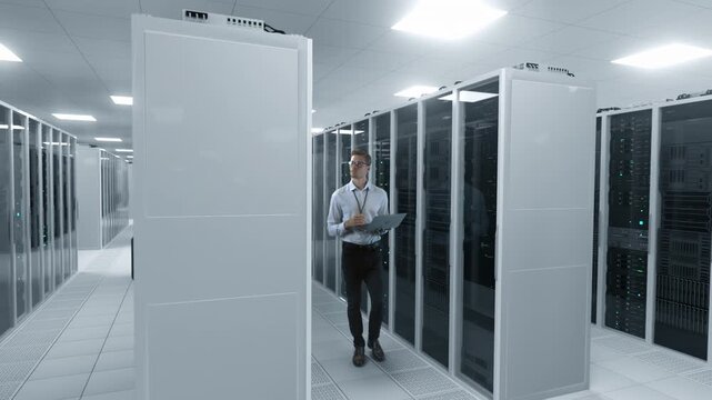 It Specialist Monitors Server Racks With a Laptop Inside a Modern Data Center, Managing Cloud Infrastructure, System Performance, Cybersecurity, Ai Workloads, and Digital Operations.