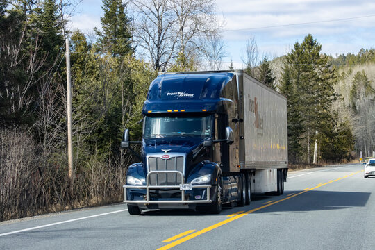 Quebec, Canada, 24 April 2026 : A TransWest Peterbilt semi truck drives on a two-lane road through a forested area.