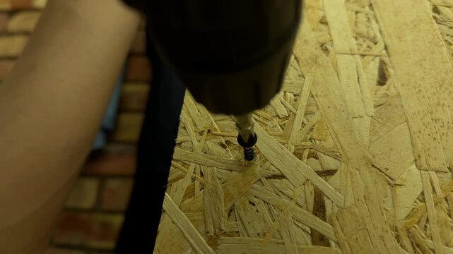 electric screwdriver removing screw from wooden board in close up, unscrewing and disassembly process, home repair concept
