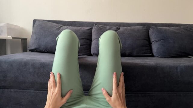 woman lifting upper body with feet supported on sofa at home, abdominal exercise, core workout, fitness training, healthy lifestyle, real people