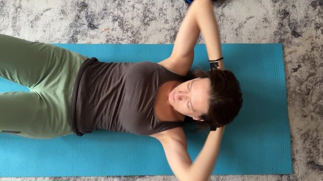 woman doing crunch exercise on mat at home, abdominal workout, fitness training, healthy lifestyle, indoor activity, real people