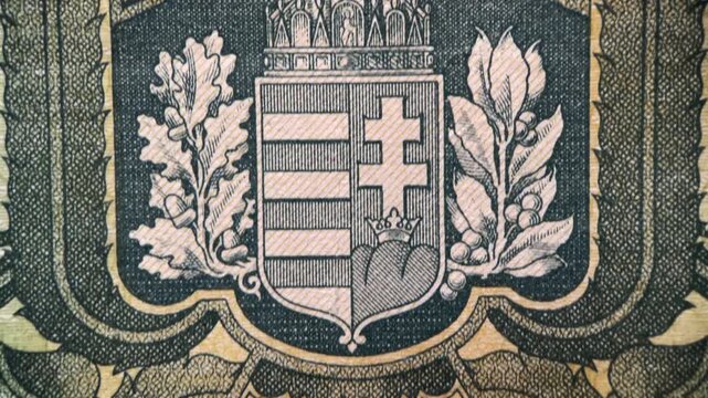 Close up video showing the reverse design of an antique Hungarian pengo banknote, featuring an engraved heraldic emblem, ornamental border details, and aged paper texture.