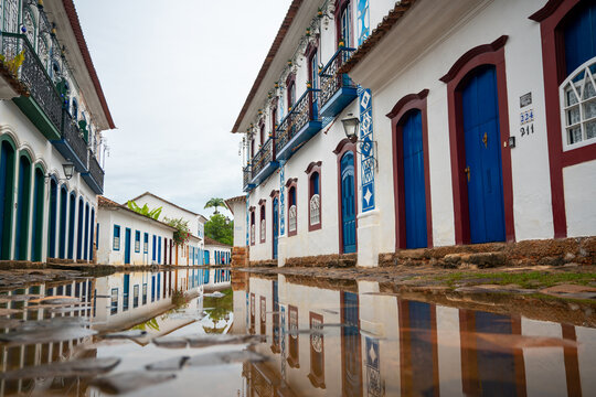 View of historic colonial buildings with colorful doors and windows reflected in a puddle on a cobblestone street Paraty, State of Rio de Janeiro, Brazil.