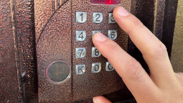 Person pressing button on door intercom keypad outdoors to open entrance door, access control action, security system use, everyday routine