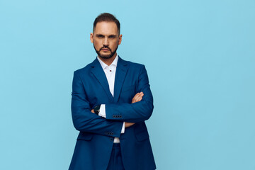 A poised business professional stands against a solid blue background, projecting confidence with crossed arms and a calm, focused gaze. The isolated color backdrop emphasizes leadership. © SHOTPRIME STUDIO