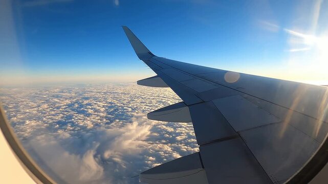 Airplane Wing View Above Clouds Through Passenger Window