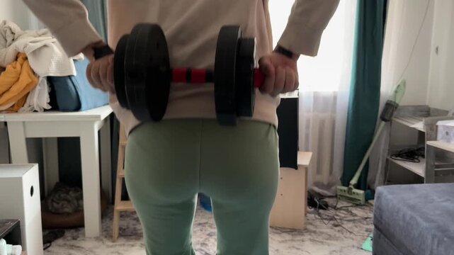 woman doing squat holding dumbbells behind back at home, lower body workout, strength training, fitness routine, healthy lifestyle, real people