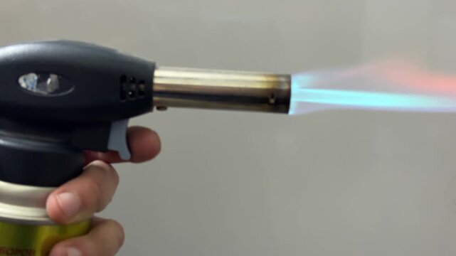 Gas torch producing blue flame close up, heating tool and workshop equipment concept