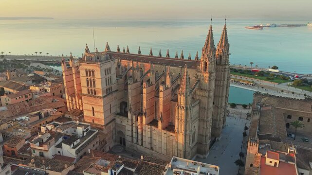 Gothic buttresses supporting La Seu cathedral in Palma de Mallorca, Spain. Monumental cathedral sits near sea in Palma de Mallorca, Spain. Sunset light hits historic church in Palma, Spain. Aerial UHD