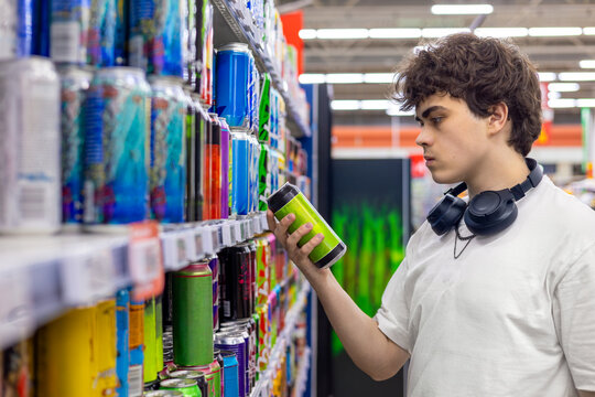 Teenager reading canned drink label in supermarket, sugar caffeine and alcohol consumption risk concept