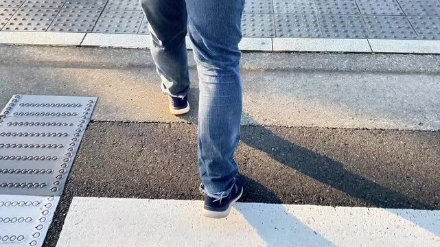  Low section of a person walking on a zebra crossing in the city.