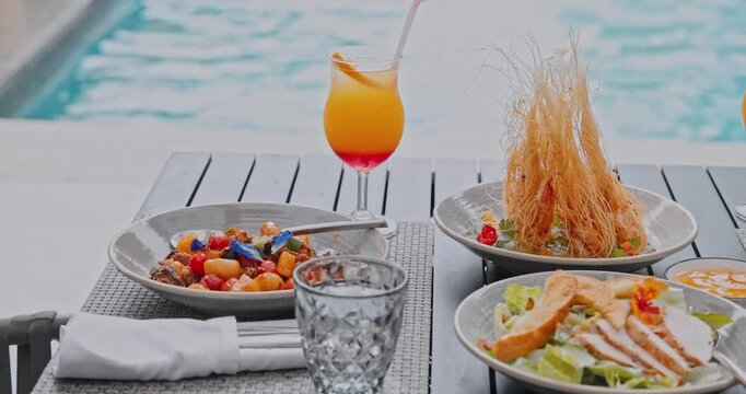 Fried prawns in kataifi pastry, chicken salad and tropical cocktail served on table, luxury poolside dining area, summer vacation lifestyle, travel and tourism marketing