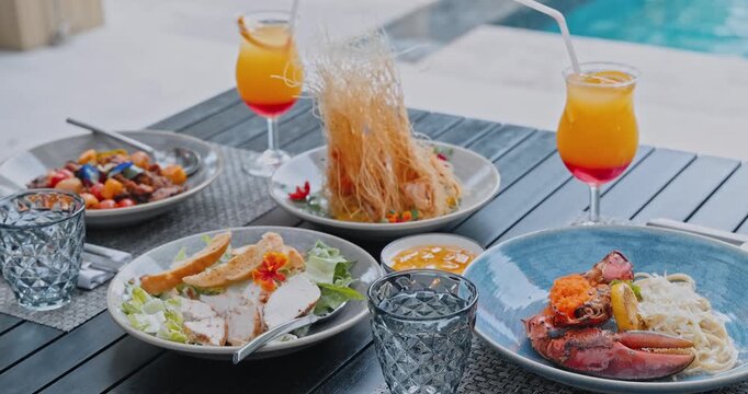 Lobster pasta with Caesar salad and cocktails sitting on wooden table, Homarus americanus served in outdoor restaurant, high-end travel gastronomy, luxury summer vacation dining