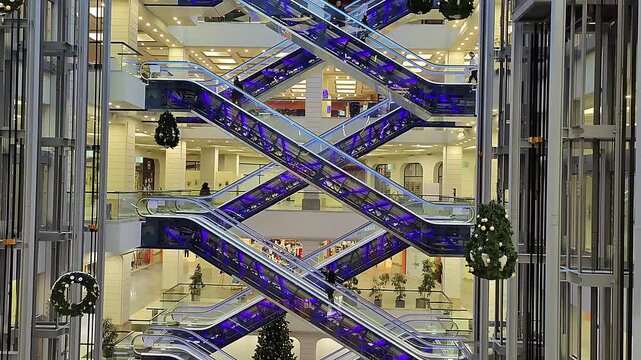 Mobile staircases in the atrium of a modern shopping mall. Geometric architectural lines with blue neon accents and glass elevator shafts.