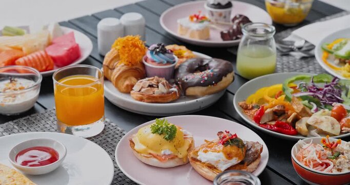 Breakfast spread including eggs benedict, chocolate donuts, fresh fruit sitting on dark table, resort morning dining patio, hospitality advertising menu content