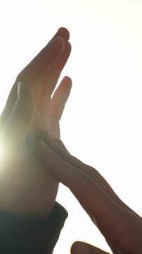 Two hands are touching in a warm light, creating a sense of connection. The hands show intimacy against a bright, soft backdrop.