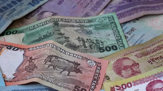 Close-up shot of various Bangladeshi Taka banknotes featuring fifty, one hundred, two hundred, five hundred, and one thousand BDT denominations, representing South Asian economy and local currency.