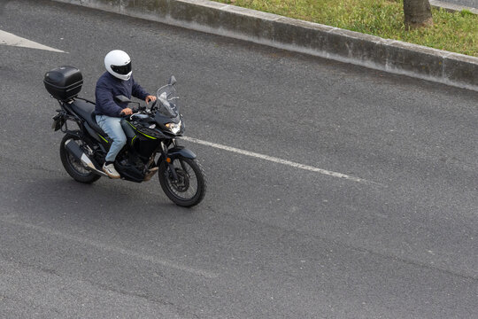 Person riding motorcycle on road commuting in city