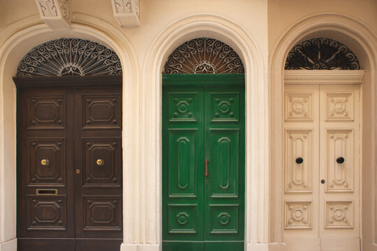 Three colorful traditional wooden doors with ornate ironwork in an arched facade