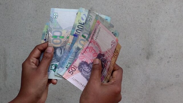 Close-up of a female hand counting South African Rand banknotes, including 20, 50, and 100 ZAR bills. Detailed footage of person handling South Africa money currency for banking and cash economy.