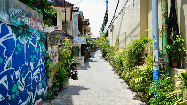 Bali Kuta streets. Life in Bali.Street with laundry shop and green plants in a neighborhood with graffiti artwork near a busy area during daytime