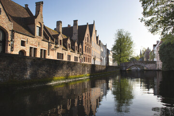 Obraz premium Scenic canal view with historic brick houses and an arched stone bridge in Bruges, Belgium