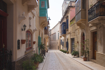 Fototapeta premium Scenic narrow street in Mdina with traditional colorful Maltese balconies