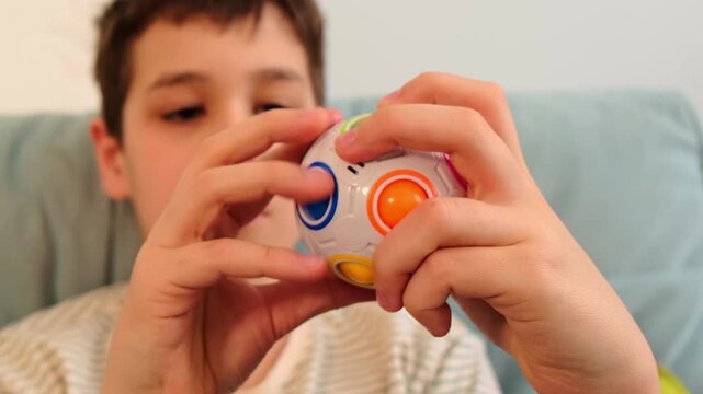 Serious child studies a fidget puzzle sphere in his hands, close up lifestyle shot with clean background. Quiet offline toys reduce stress, train patience, and keep kids engaged at home.