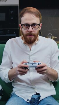 Focused man playing video game in moderm kitchen apartment enjoying indoor activity. Online entertainment and leisure activity concept. Slow motion.