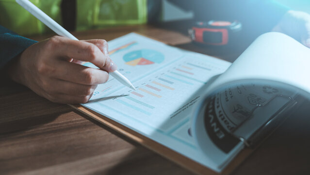 Green construction environmental sustainability ESG concept engineer hand with pen pointing at net zero report chart cost estimation eco friendly building project management tape measure