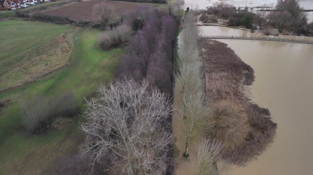 Low Aerial Flight Over Flooded Bare Trees and Muddy Floodwater in Wicksteed Park Northamptonshire