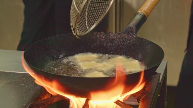 Traditional cuisine of ancient nomads. Festive dish for Nauryz.
Person stirring baursaks in cast iron cauldron with slotted spoon. The national bread of the Kyrgyz, Tajiks, Uzbeks 
